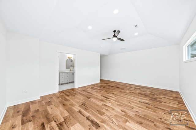 interior space featuring light wood-type flooring, vaulted ceiling, and visible vents