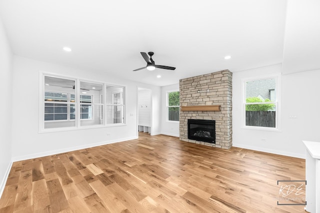 unfurnished living room with baseboards, light wood finished floors, ceiling fan, and a fireplace