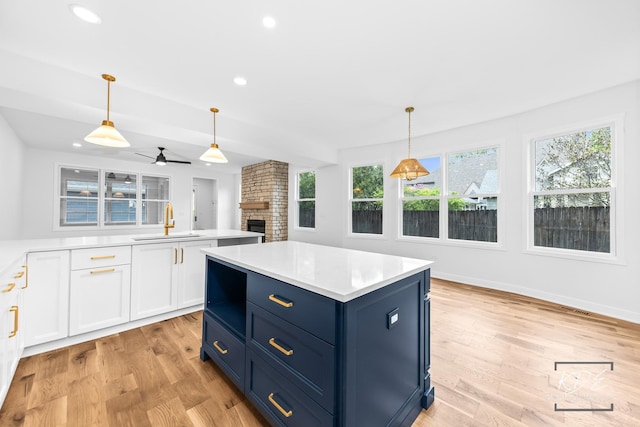 kitchen featuring a sink, plenty of natural light, a fireplace, and a ceiling fan