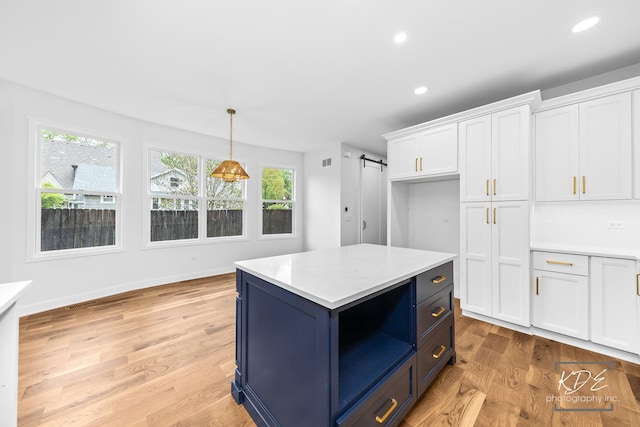 kitchen featuring a barn door, white cabinetry, light countertops, blue cabinets, and decorative light fixtures