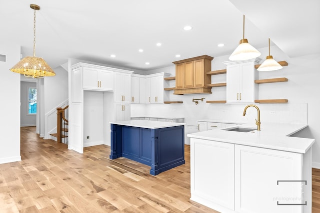 kitchen with light wood-style flooring, open shelves, a sink, and blue cabinetry