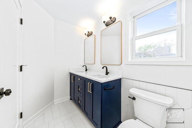 bathroom with double vanity, a sink, tile patterned floors, and toilet