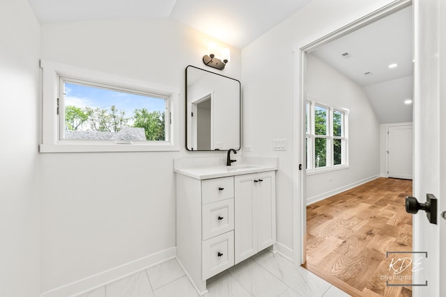 bathroom with baseboards, lofted ceiling, and vanity
