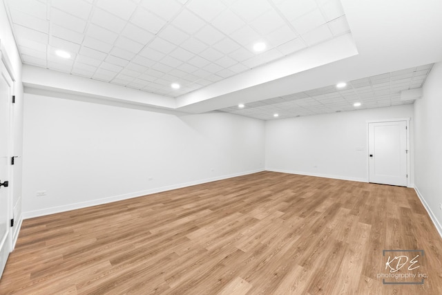 finished below grade area featuring baseboards, recessed lighting, light wood-style flooring, and a paneled ceiling