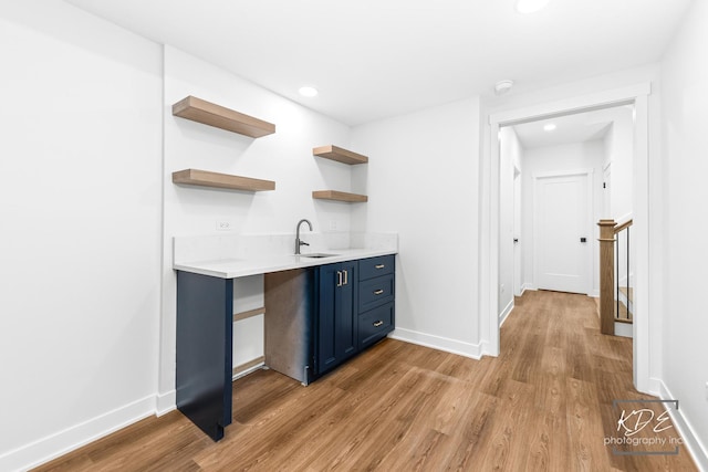 bar featuring a sink, baseboards, recessed lighting, and light wood-style flooring