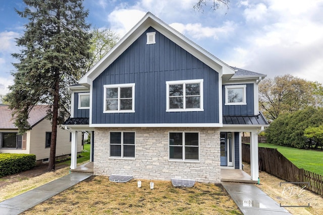 view of front of house with a standing seam roof, covered porch, and stone siding