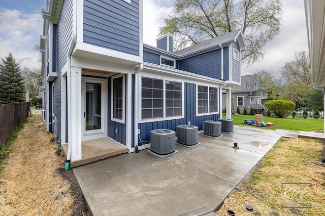 back of property featuring a lawn, cooling unit, a chimney, and a patio area