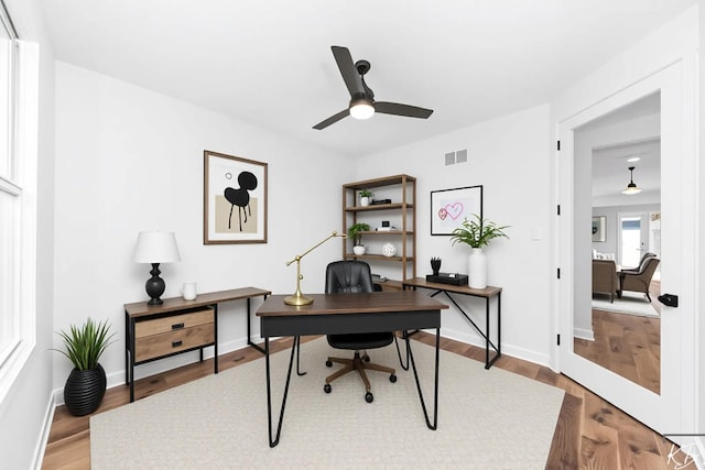 office area with baseboards, a ceiling fan, wood finished floors, and visible vents