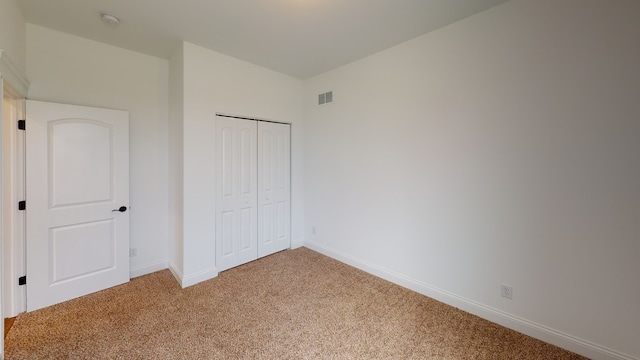 unfurnished bedroom featuring light carpet and a closet