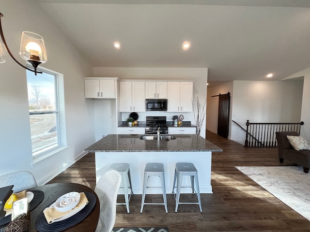 kitchen featuring dark hardwood / wood-style floors, an island with sink, white cabinets, and gas range