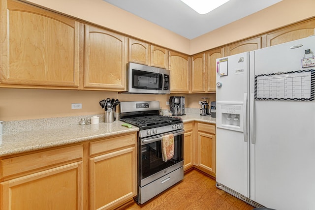 kitchen with appliances with stainless steel finishes, light hardwood / wood-style flooring, and light brown cabinetry