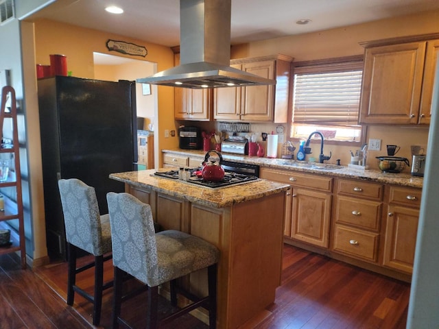 kitchen featuring dark hardwood / wood-style floors, island exhaust hood, black fridge, a center island, and sink