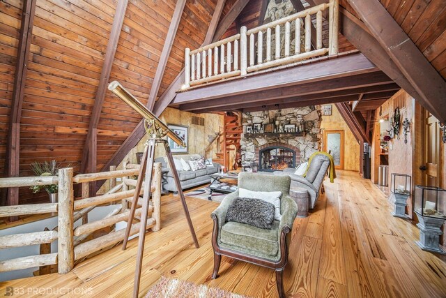 unfurnished living room featuring wood walls, high vaulted ceiling, a fireplace, light hardwood / wood-style floors, and wood ceiling