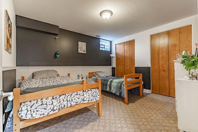 bedroom featuring two closets and light colored carpet