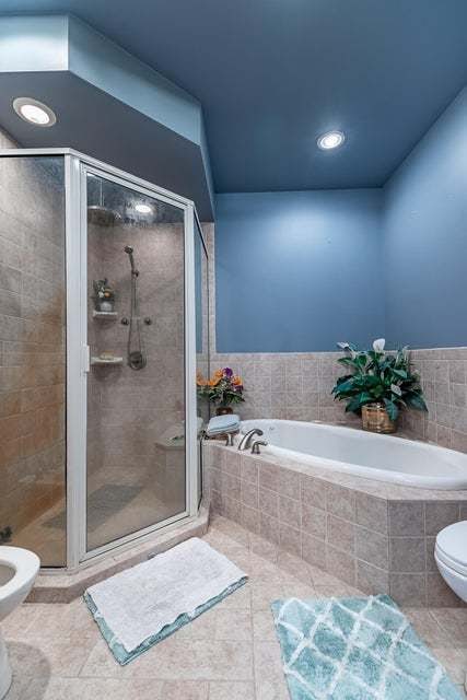 bathroom featuring independent shower and bath, tile patterned flooring, and toilet