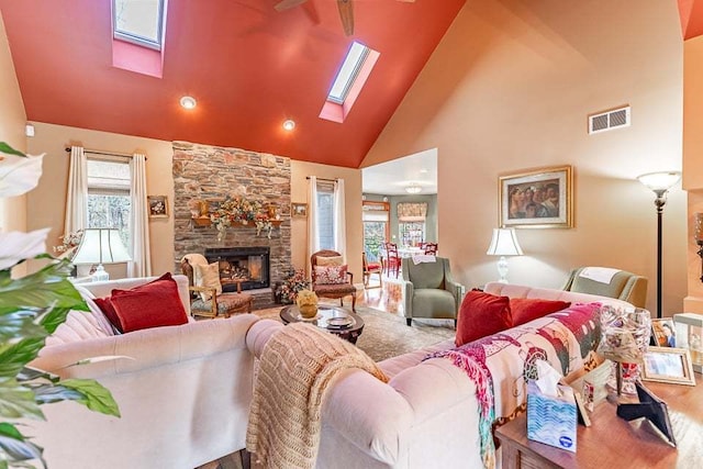 living room featuring a skylight, high vaulted ceiling, ceiling fan, a fireplace, and hardwood / wood-style flooring