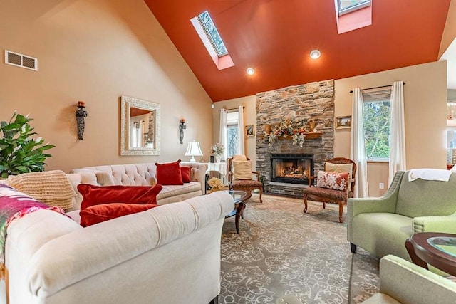 living room featuring a skylight, a stone fireplace, and high vaulted ceiling