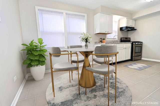 kitchen with light tile patterned flooring, white cabinets, and stainless steel stove