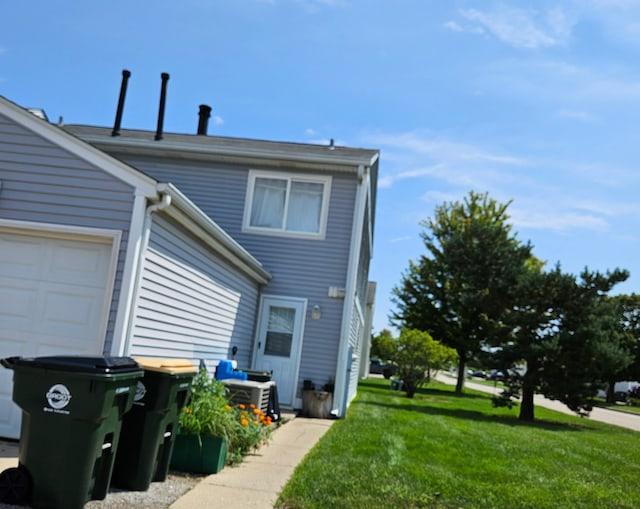 view of side of home featuring central air condition unit, a garage, and a yard