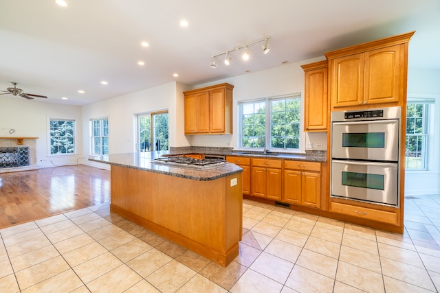 kitchen featuring light hardwood / wood-style flooring, stainless steel appliances, ceiling fan, and a healthy amount of sunlight