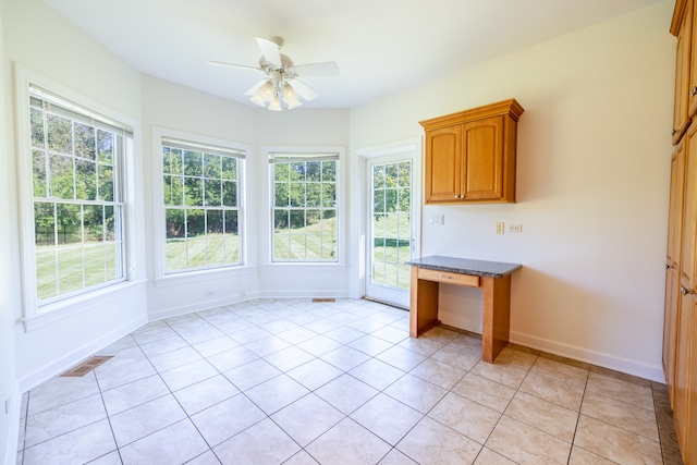 kitchen featuring ceiling fan, light tile patterned floors, and dark stone countertops