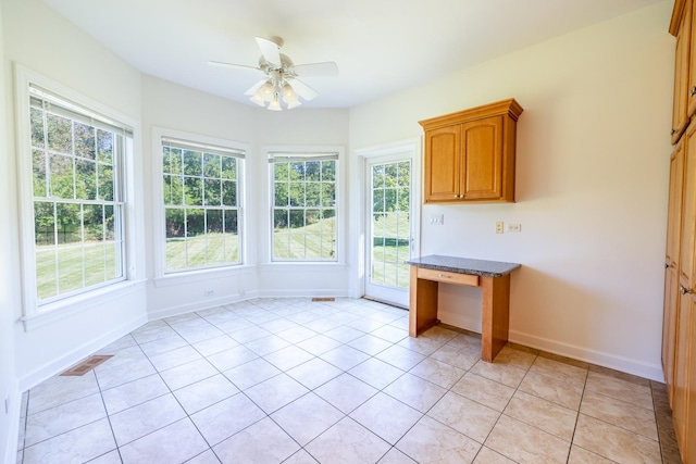 unfurnished sunroom with built in desk, visible vents, and a ceiling fan