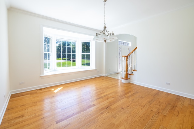 spare room featuring crown molding, light hardwood / wood-style flooring, and a notable chandelier