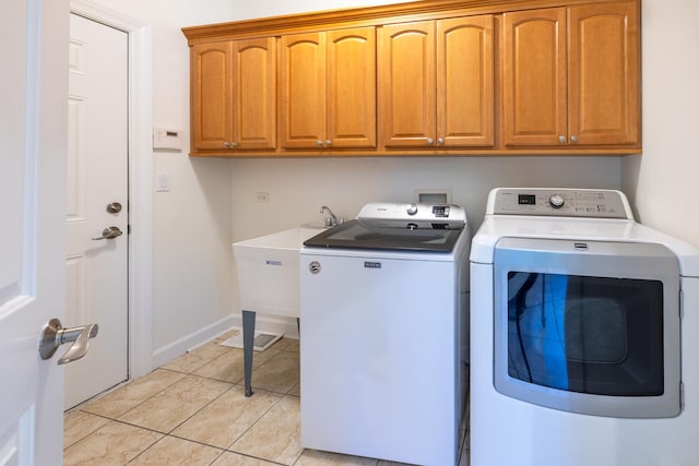 laundry area featuring cabinet space, light tile patterned floors, baseboards, and independent washer and dryer