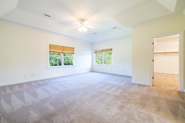 unfurnished bedroom with a tray ceiling, multiple windows, and ceiling fan