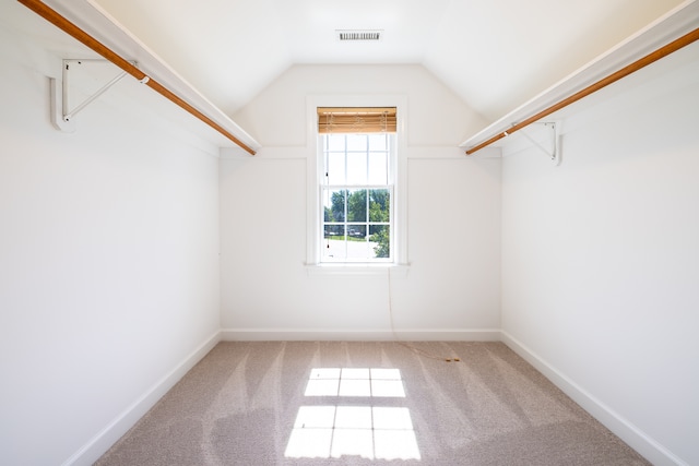 walk in closet with light carpet and lofted ceiling