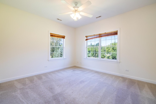 empty room with baseboards, ceiling fan, visible vents, and light colored carpet