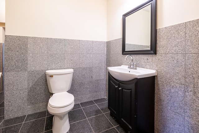 half bathroom featuring toilet, a wainscoted wall, tile patterned floors, and vanity