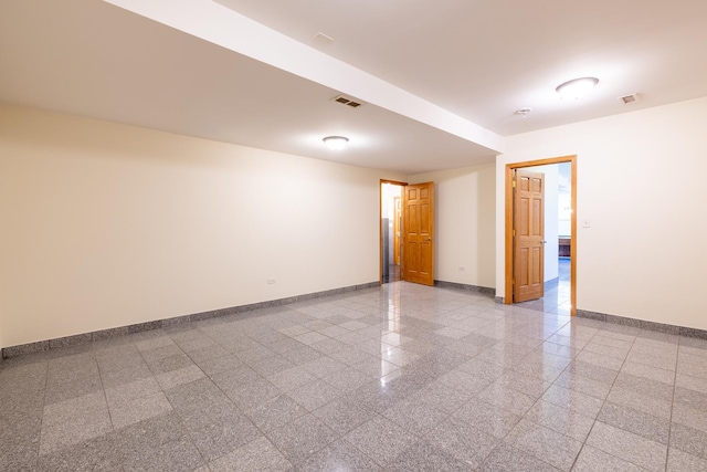 spare room featuring granite finish floor, visible vents, and baseboards