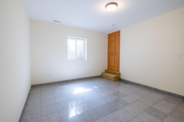 spare room with visible vents, granite finish floor, and baseboards