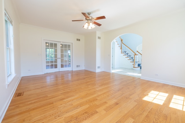 empty room with crown molding, french doors, light hardwood / wood-style flooring, and ceiling fan