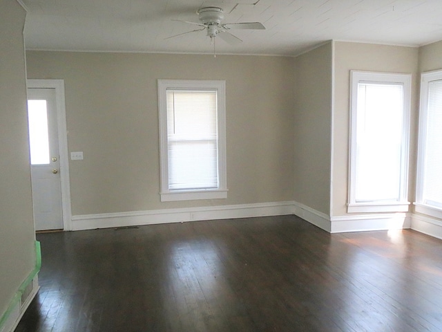 empty room featuring dark wood-type flooring, a healthy amount of sunlight, and ceiling fan