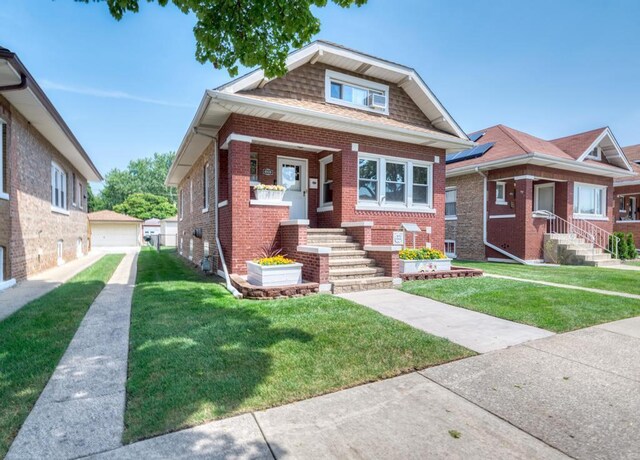 bungalow-style house featuring an outbuilding, a front lawn, and a garage