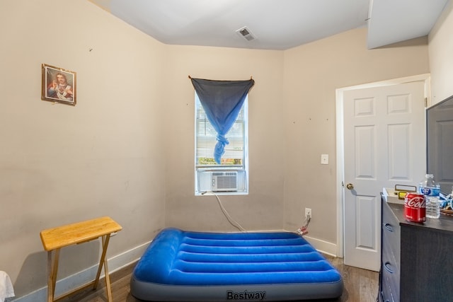 bedroom with cooling unit and hardwood / wood-style flooring