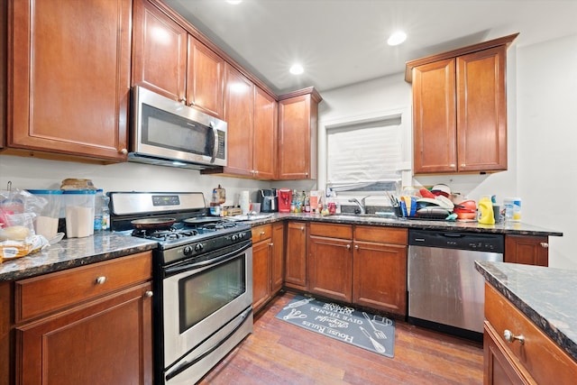 kitchen with dark stone counters, light hardwood / wood-style flooring, appliances with stainless steel finishes, and sink