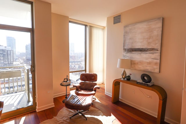 living area featuring a view of city, a wall of windows, dark wood-style floors, and baseboards