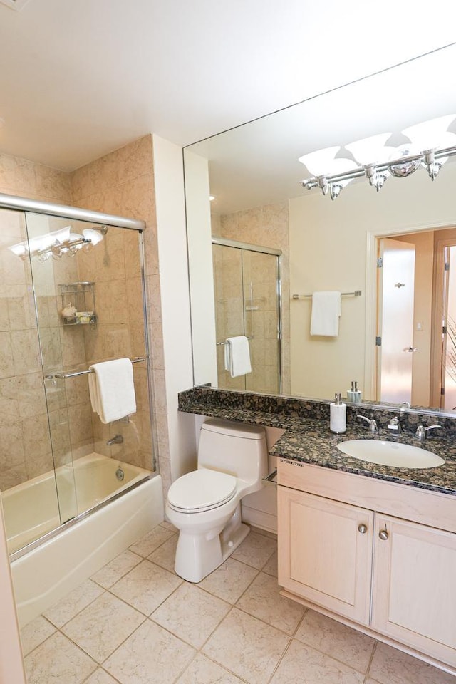 full bath with tile patterned flooring, vanity, toilet, and bath / shower combo with glass door