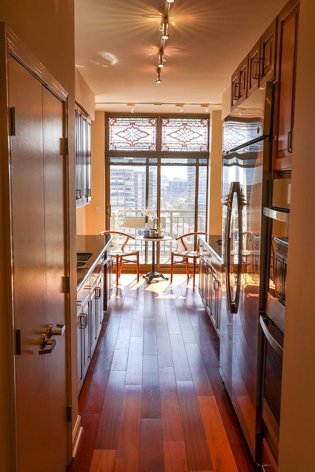 kitchen featuring dark wood finished floors, dark countertops, expansive windows, oven, and fridge