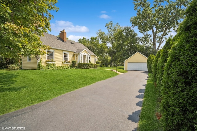 new england style home featuring a garage, an outdoor structure, and a front yard