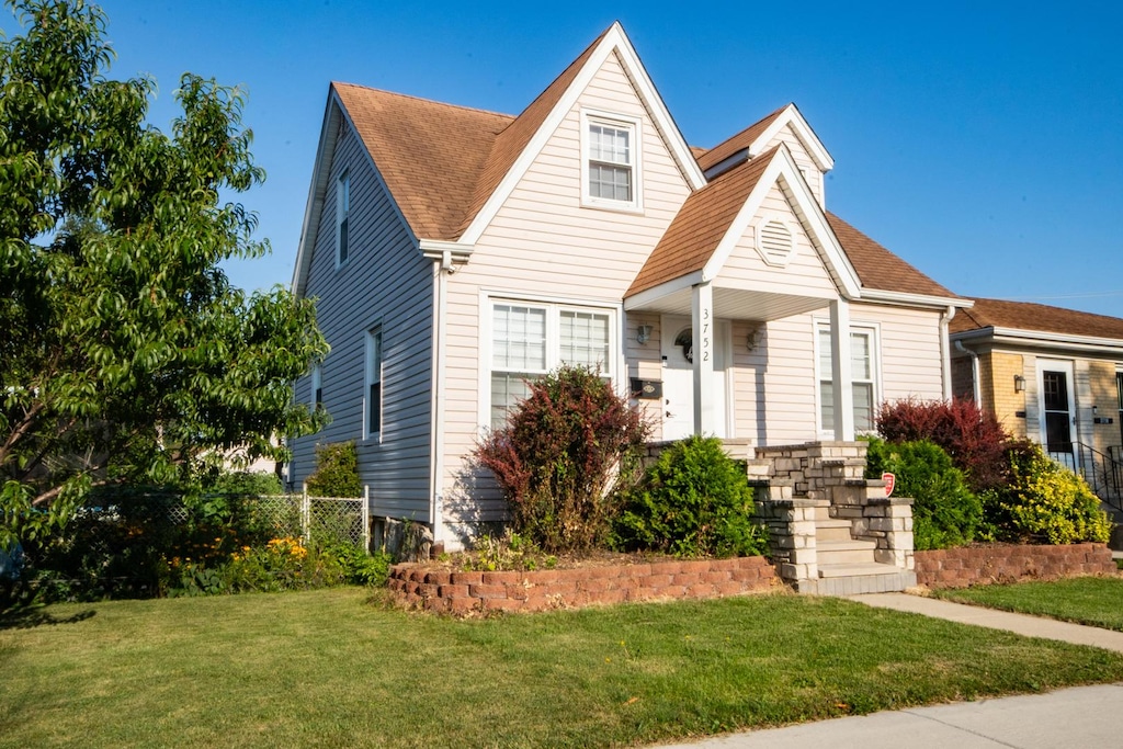 view of front of property featuring fence, a front lawn, and roof with shingles