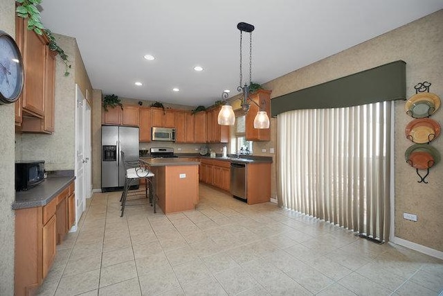 kitchen featuring a kitchen island, a kitchen bar, hanging light fixtures, light tile patterned floors, and stainless steel appliances