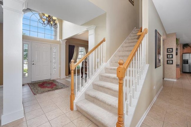 entrance foyer featuring a notable chandelier, light tile patterned flooring, and ornate columns