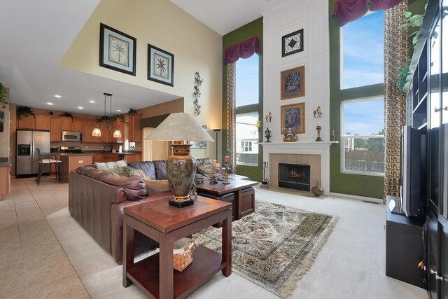 living room with light tile patterned floors, a tile fireplace, a healthy amount of sunlight, and a high ceiling