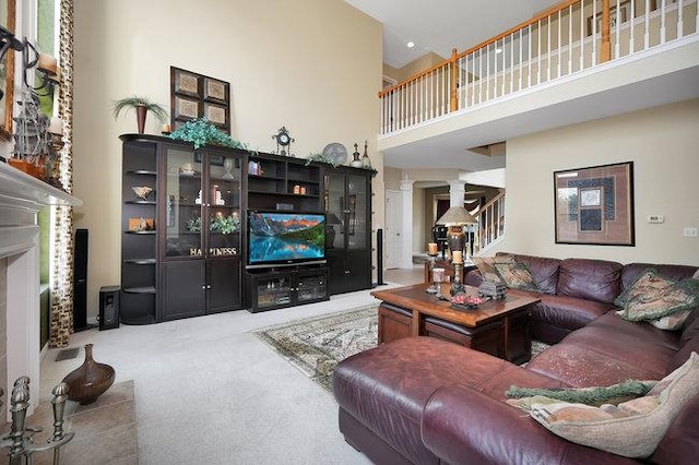 living room with a towering ceiling, a high end fireplace, decorative columns, and carpet flooring