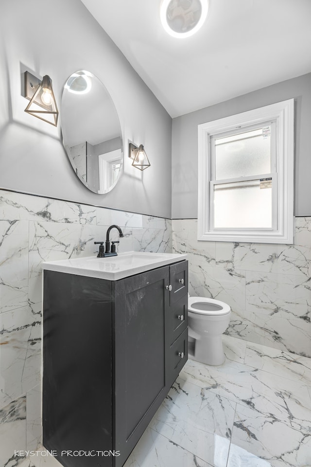 bathroom featuring tile patterned floors, vanity, tile walls, and toilet