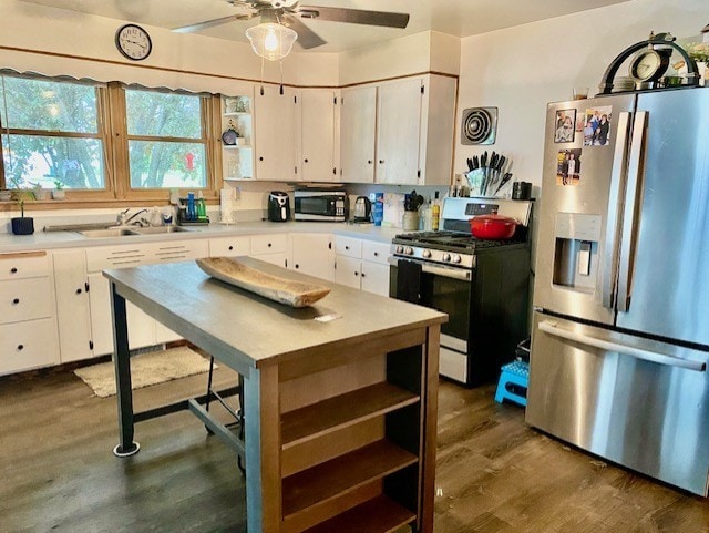 kitchen featuring dark wood-type flooring, appliances with stainless steel finishes, white cabinets, ceiling fan, and sink